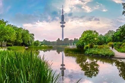 Hermosa vista del jardín de flores en el parque Planten um Blomen con la famosa torre de telecomunicaciones de radio Heinrich-Hertz-Turm en el fondo al atardecer, Hamburgo, Alemania